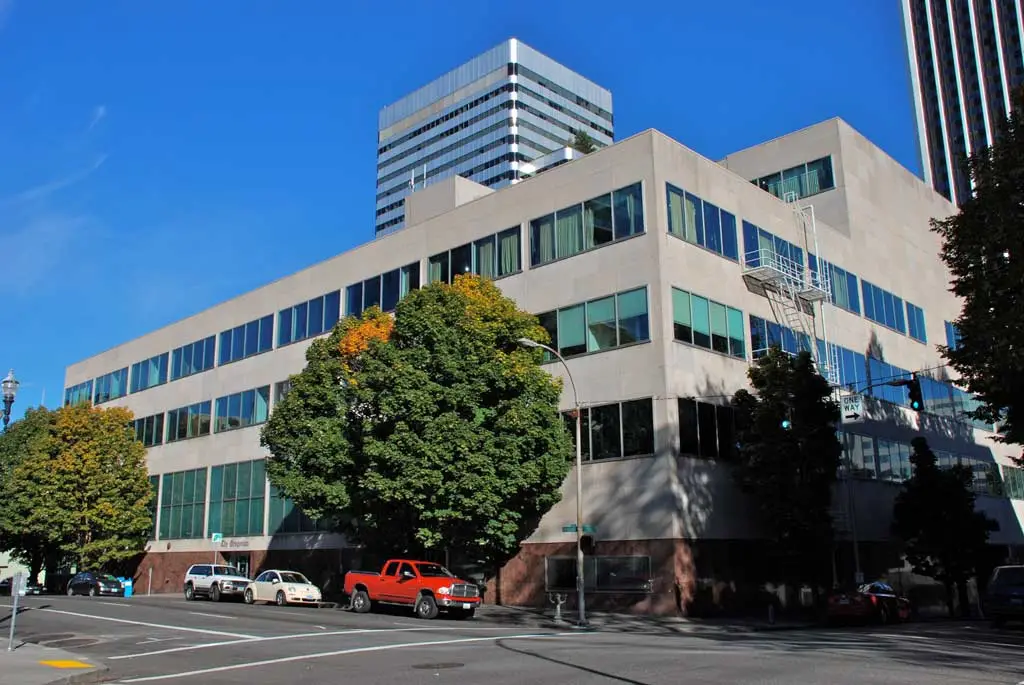 Mid-century office building with green and beige exterior and street parking