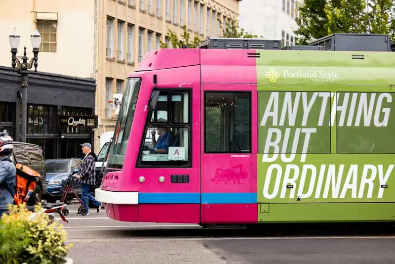 Bright pink Portland Streetcar with slogan “Anything but Ordinary”